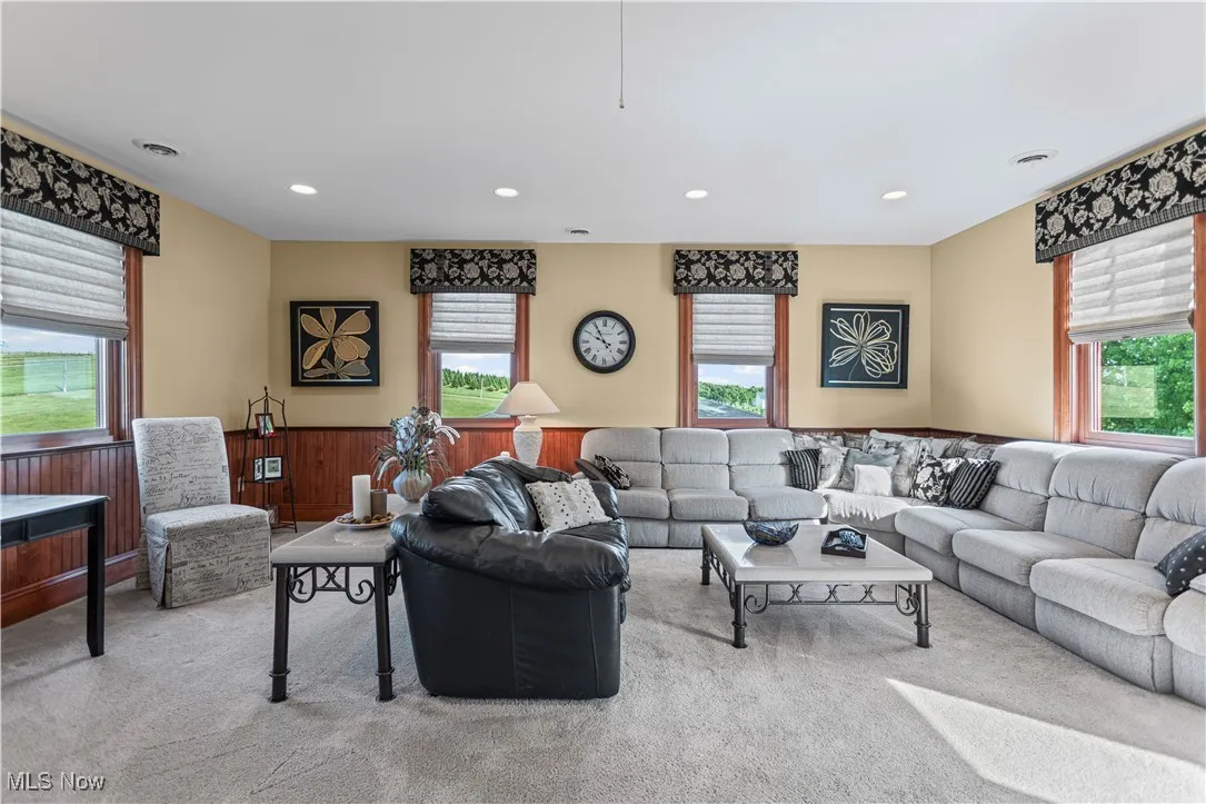 Carpeted living room with healthy amount of natural light, recessed lighting, and wainscoting