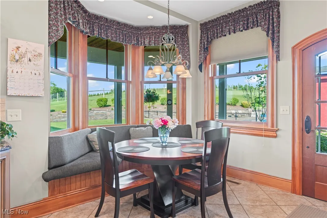 Tiled dining room with a chandelier and baseboards