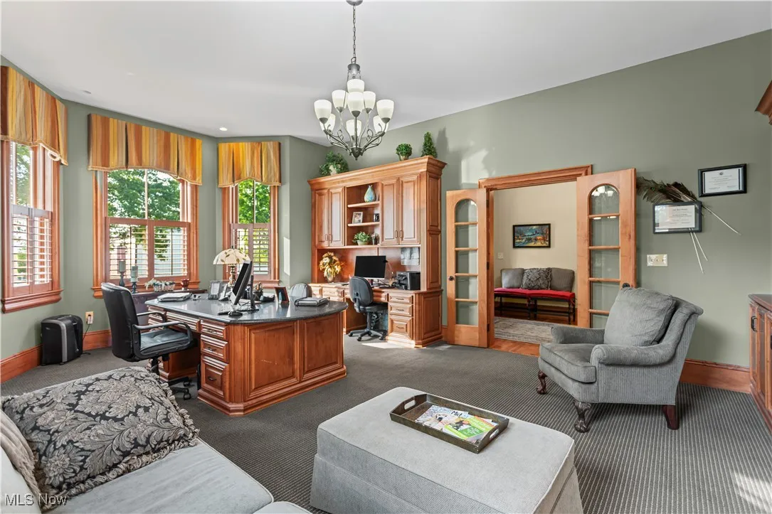 Office space featuring dark carpet, a chandelier, baseboards, and built in study area