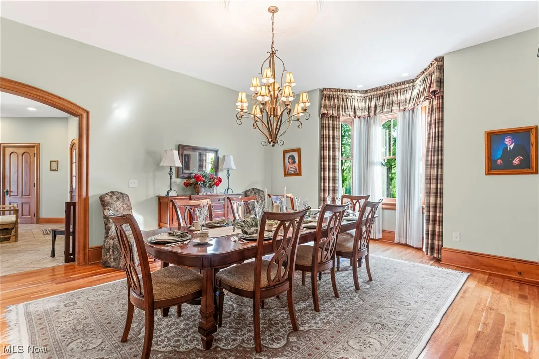 Dining room featuring a chandelier, baseboards, light wood-style flooring, arched walkways, and recessed lighting