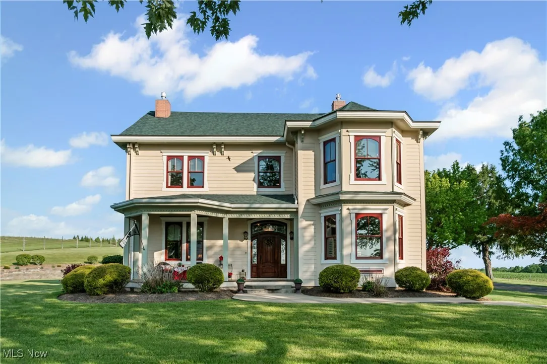 View of front facade with a front yard, a porch, a chimney, and roof with shingles
