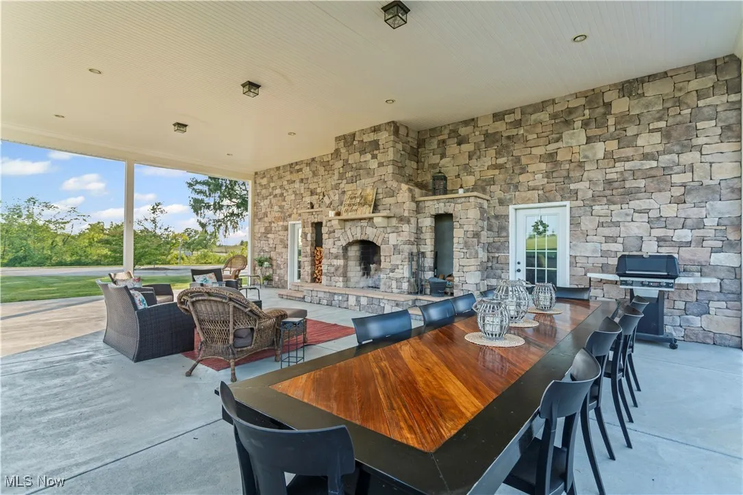 View of patio featuring area for grilling, outdoor dining space, and an outdoor living space with a fireplace