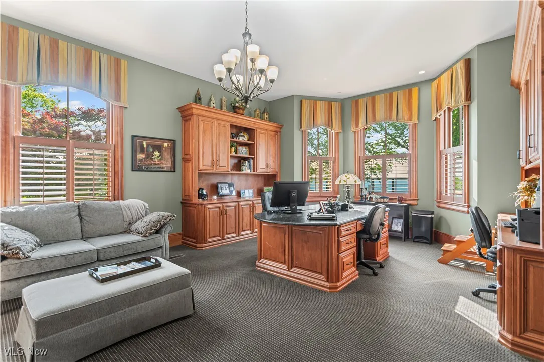 Office with a chandelier, dark carpet, and baseboards