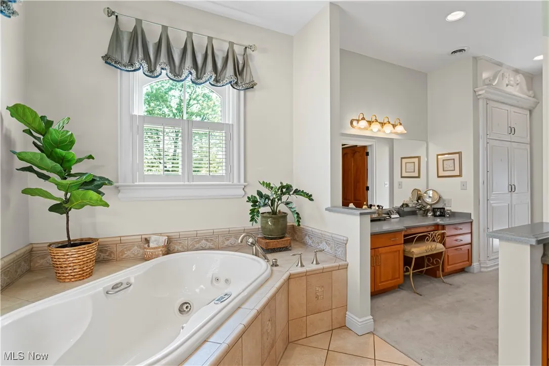 Full bath featuring vanity, a tub with jets, and tile patterned flooring