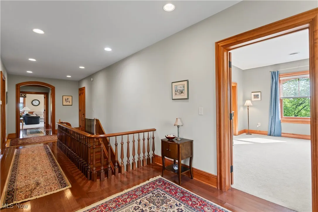 Corridor with baseboards, wood finished floors, recessed lighting, an upstairs landing, and arched walkways