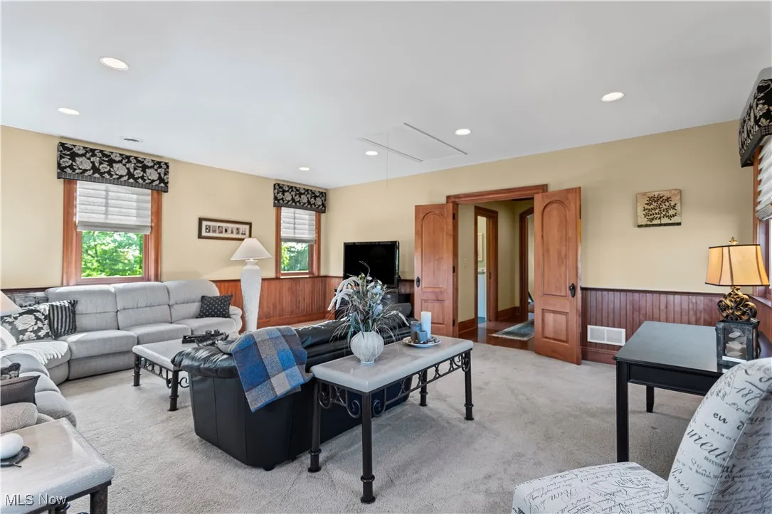 Living area with attic access, light carpet, a wainscoted wall, recessed lighting, and wood walls