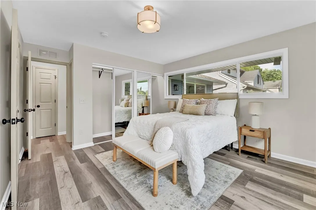 Bedroom featuring wood finished floors, baseboards, and multiple closets