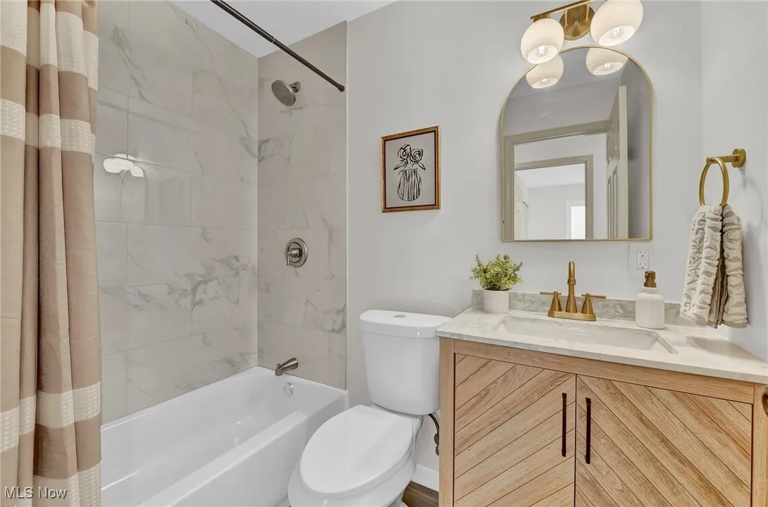 Full bathroom featuring shower / bathtub combination with curtain, vanity, and toilet