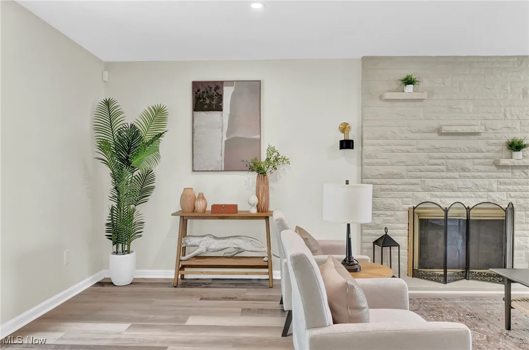Living area with a stone fireplace, baseboards, wood finished floors, and recessed lighting