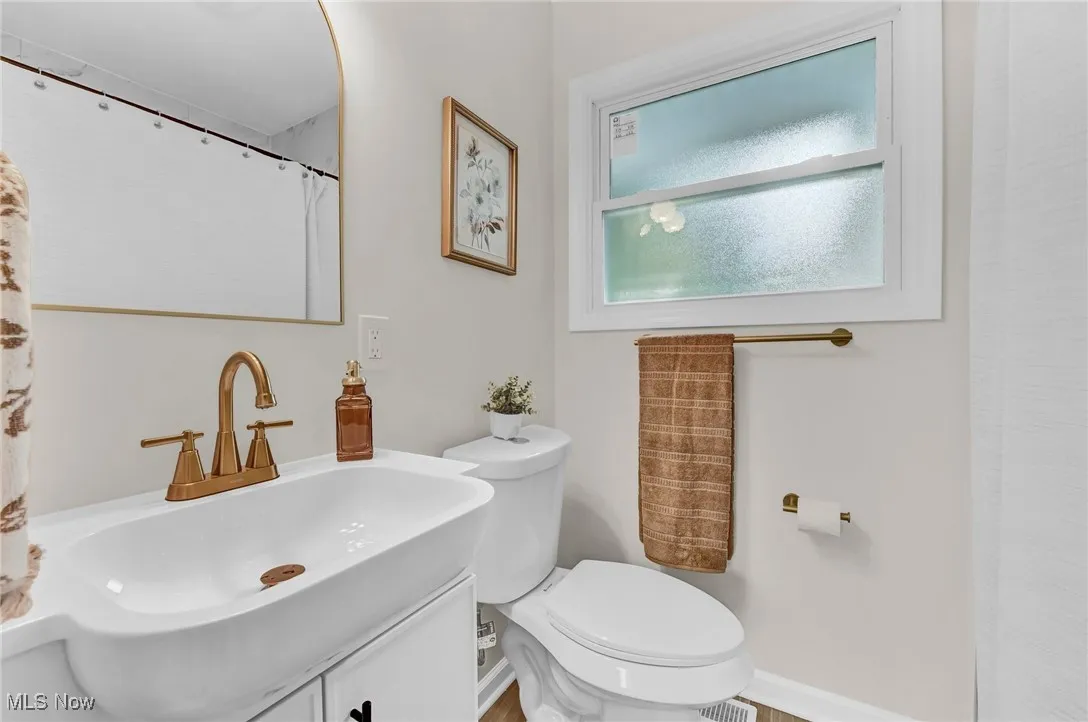 Bathroom featuring vanity, toilet, and baseboards