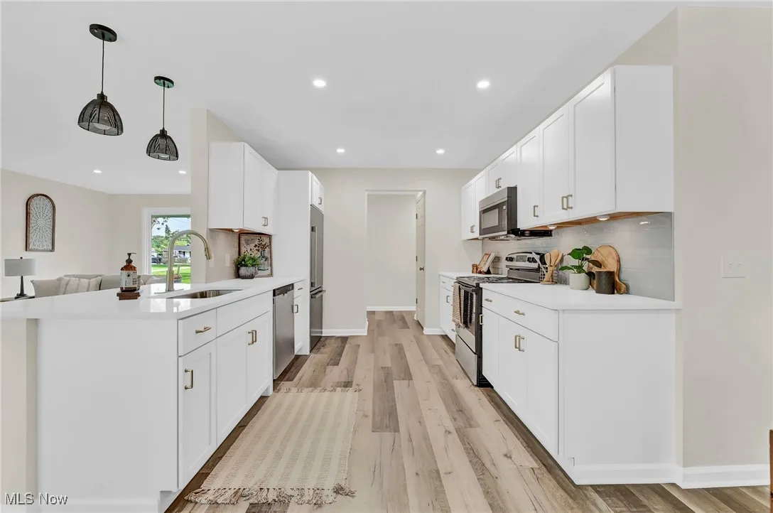 Kitchen with stainless steel appliances, a sink, tasteful backsplash, light countertops, and recessed lighting