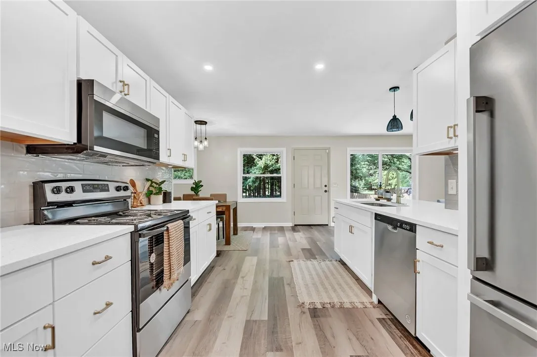 Kitchen with appliances with stainless steel finishes, light countertops, light wood-style floors, white cabinetry, and recessed lighting