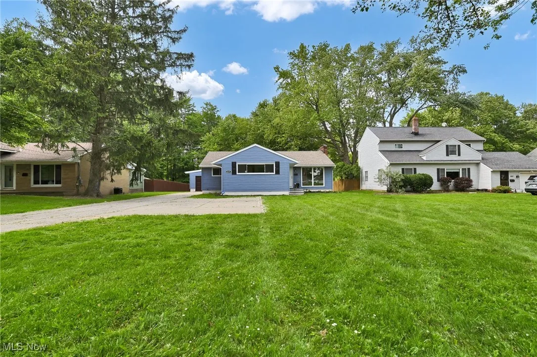 View of front of house featuring a chimney, a front yard, and driveway