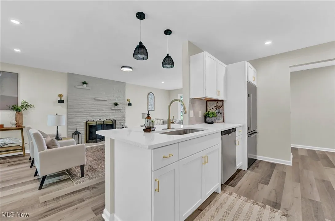 Kitchen with a sink, appliances with stainless steel finishes, light wood-type flooring, white cabinets, and open floor plan