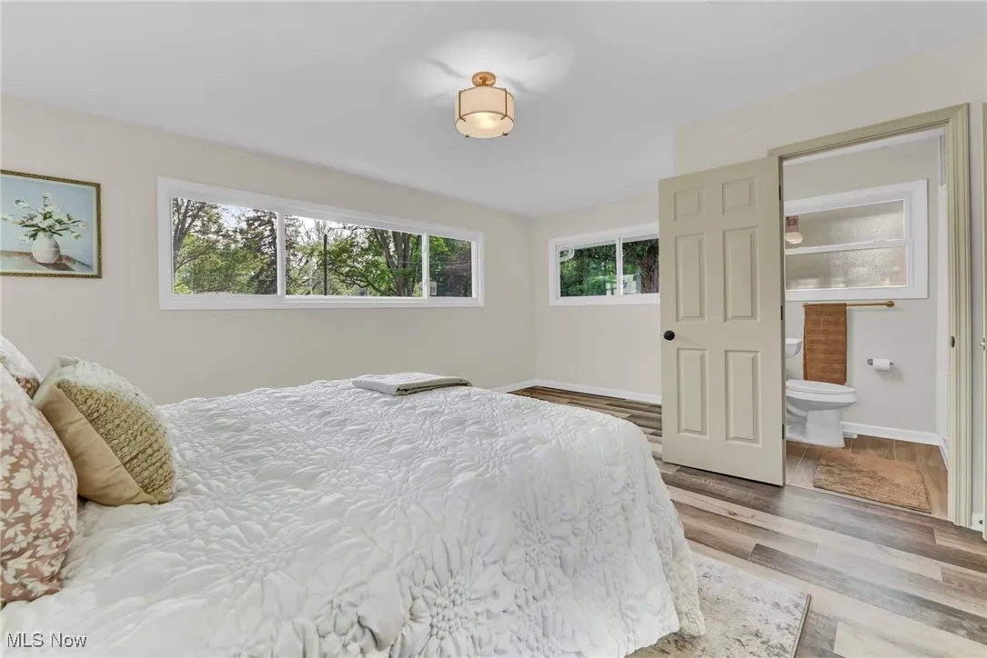 Bedroom featuring wood finished floors, connected bathroom, and baseboards