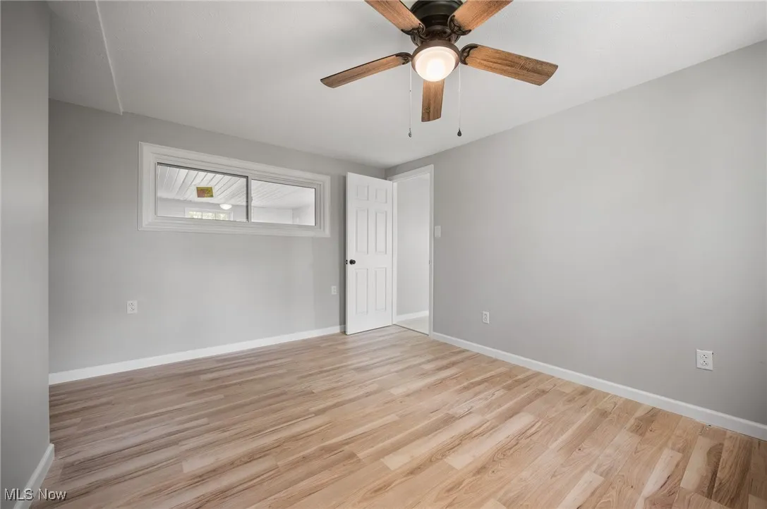 Spare room featuring light wood-style floors, baseboards, and a ceiling fan