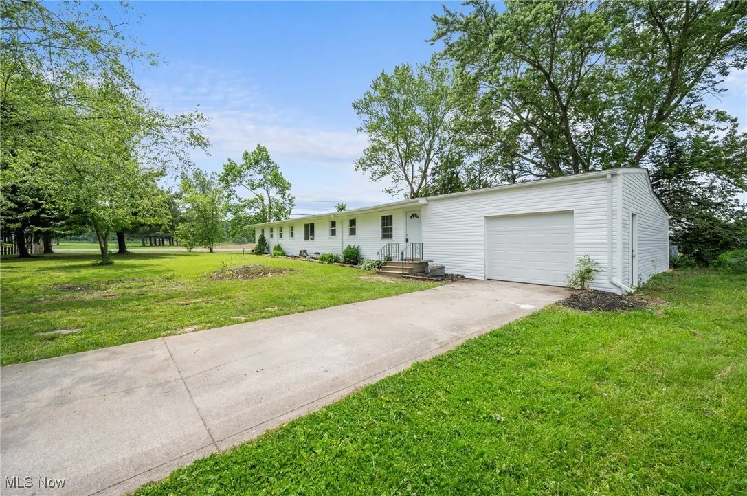 View of front of home with an attached garage, driveway, and a front lawn