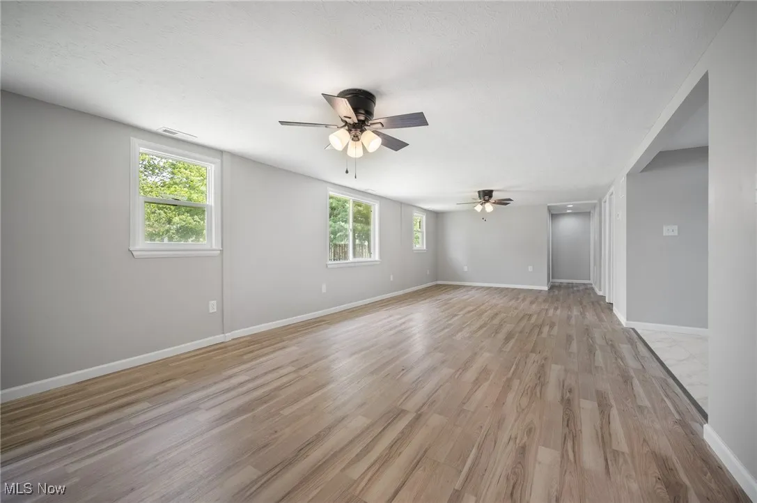Unfurnished room with ceiling fan, light wood-style floors, and baseboards