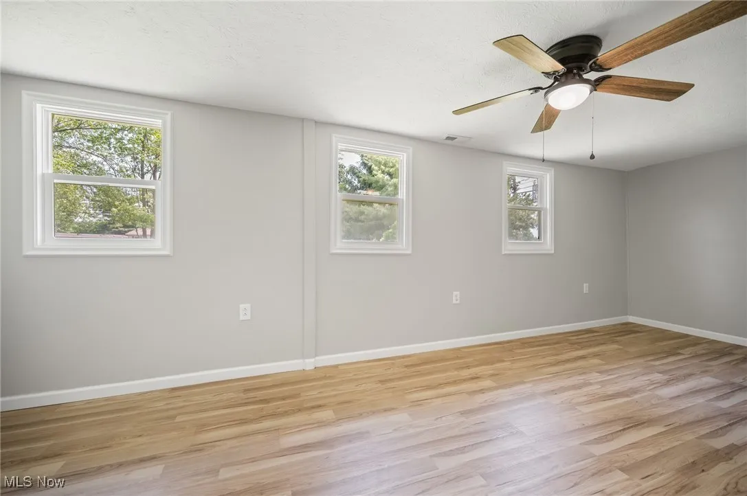 Spare room featuring light wood finished floors, baseboards, and a ceiling fan