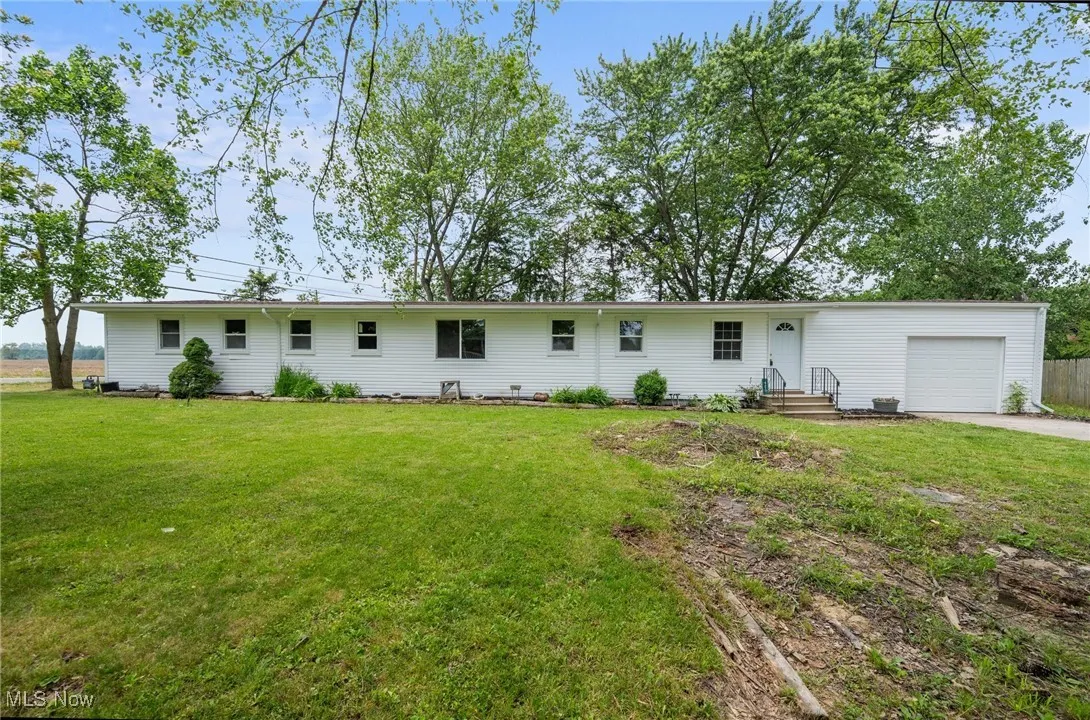 Rear view of property featuring a garage, concrete driveway, and a yard