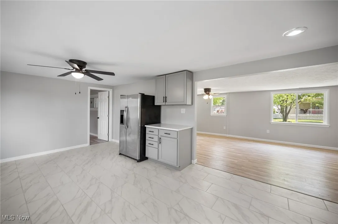 Kitchen featuring stainless steel fridge, gray cabinets, a ceiling fan, and open floor plan