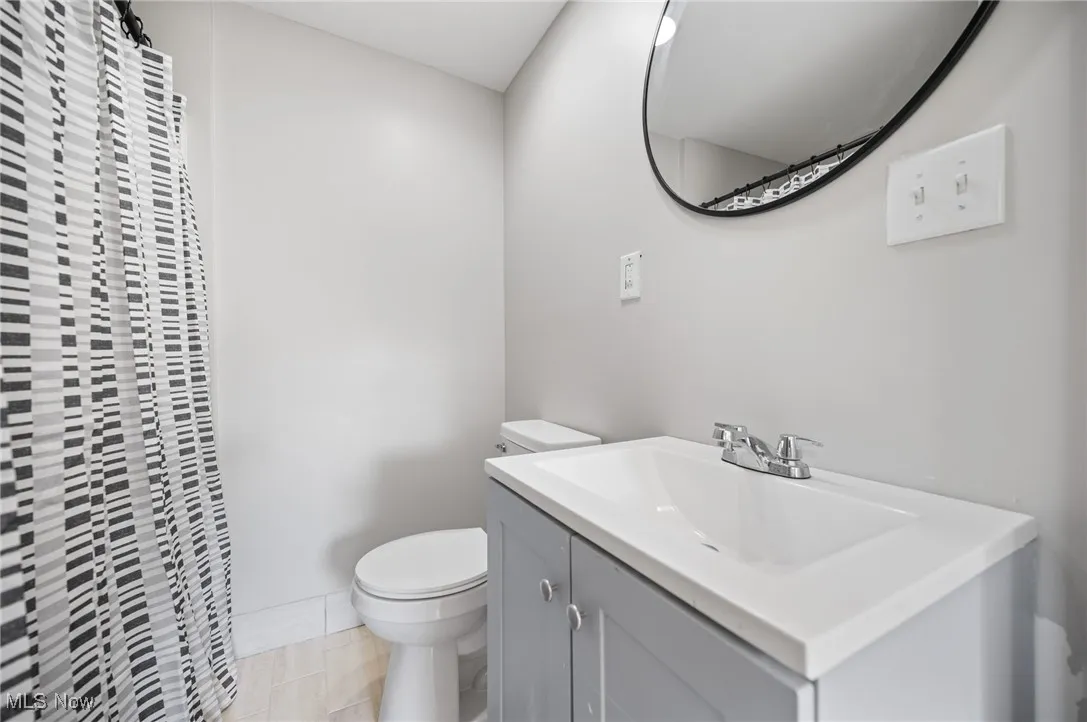 Full bathroom with toilet, vanity, and a shower with shower curtain