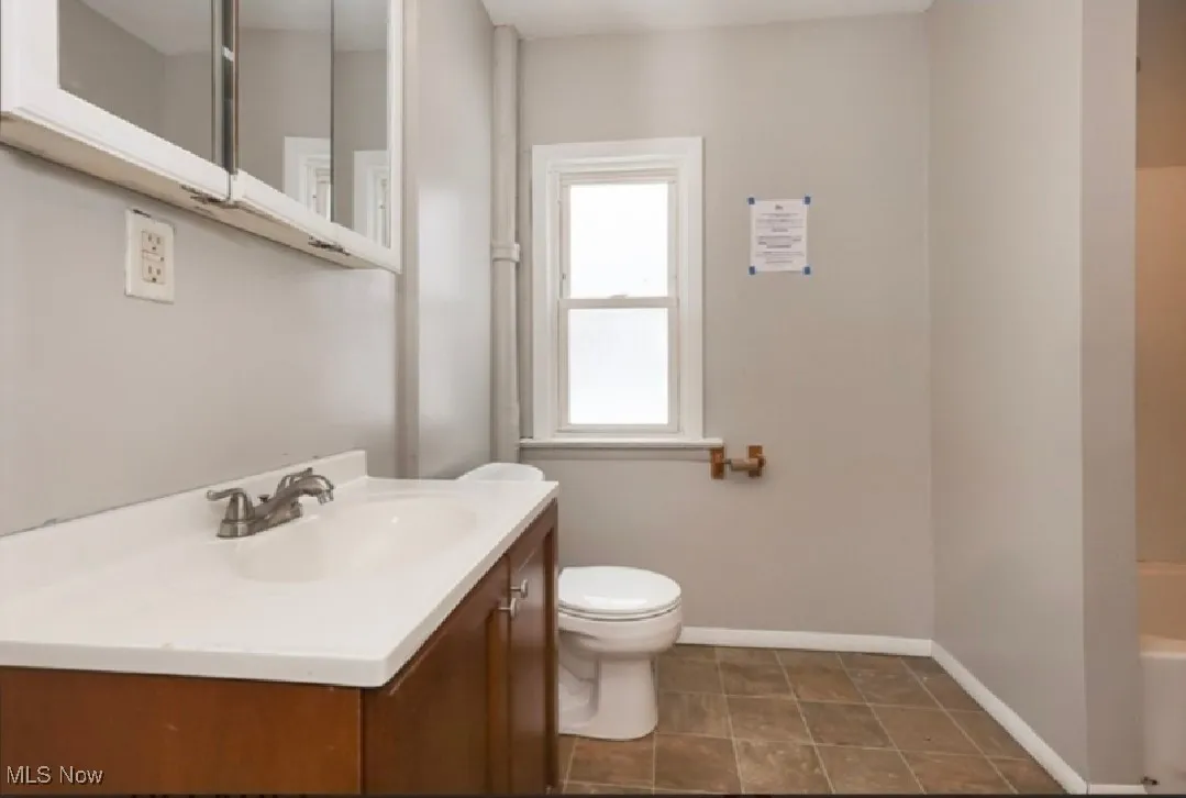 Full bathroom featuring toilet, vanity, a bathtub, and baseboards