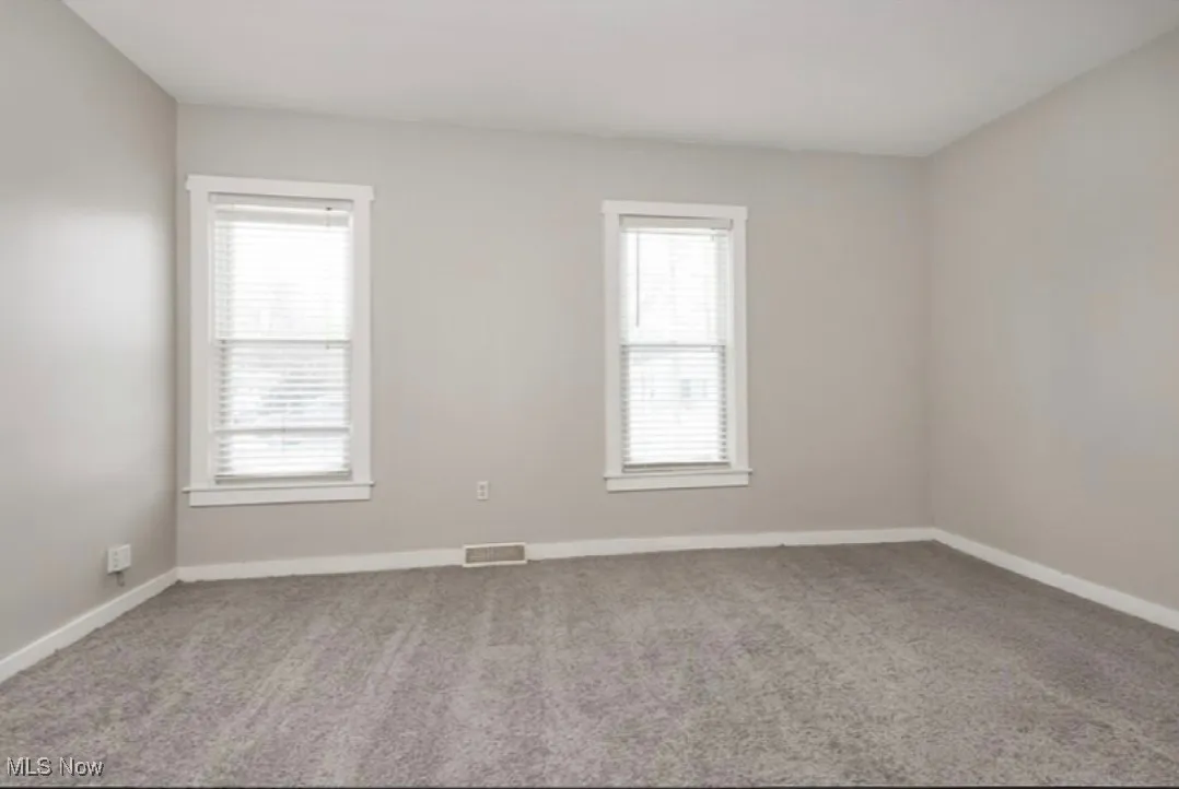 Carpeted spare room featuring baseboards