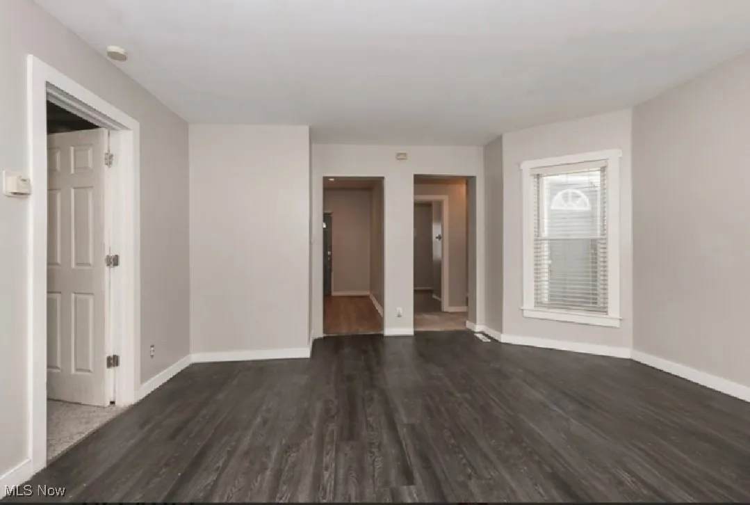 Spare room featuring dark wood-style floors and baseboards