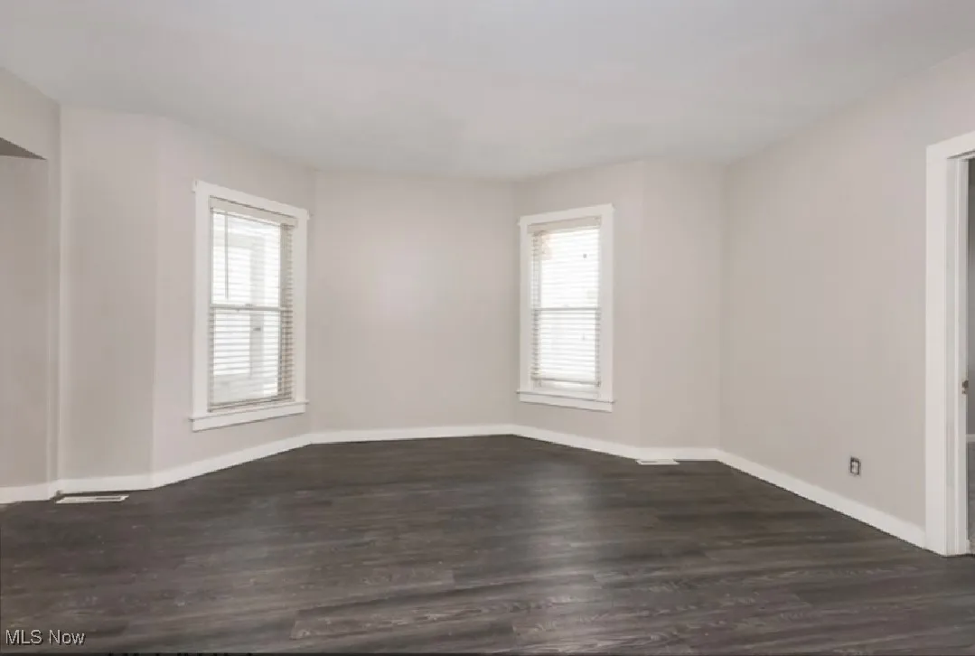 Spare room featuring dark wood-style floors and baseboards