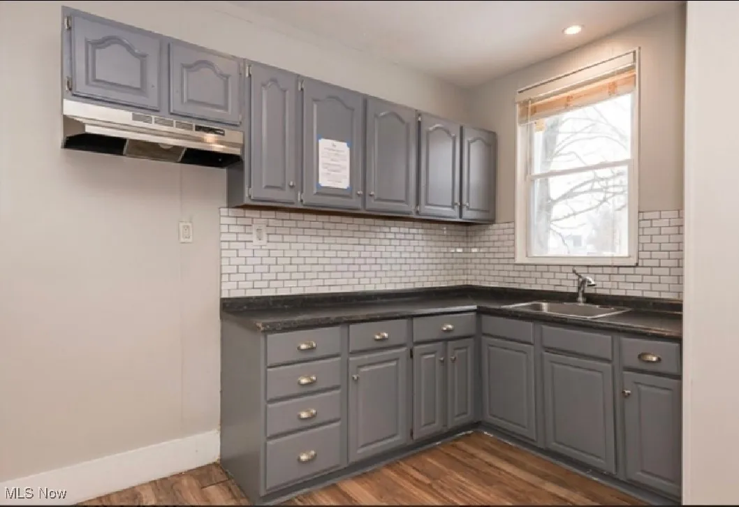 Kitchen with gray cabinetry, dark countertops, dark wood finished floors, a sink, and recessed lighting