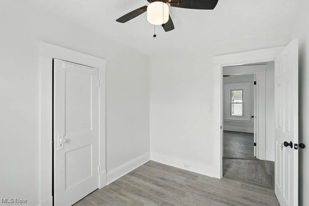 Empty room featuring baseboards, light wood-type flooring, and ceiling fan