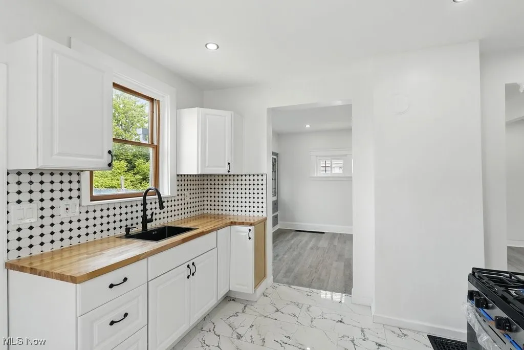 Kitchen with butcher block counters, a sink, recessed lighting, backsplash, and white cabinets