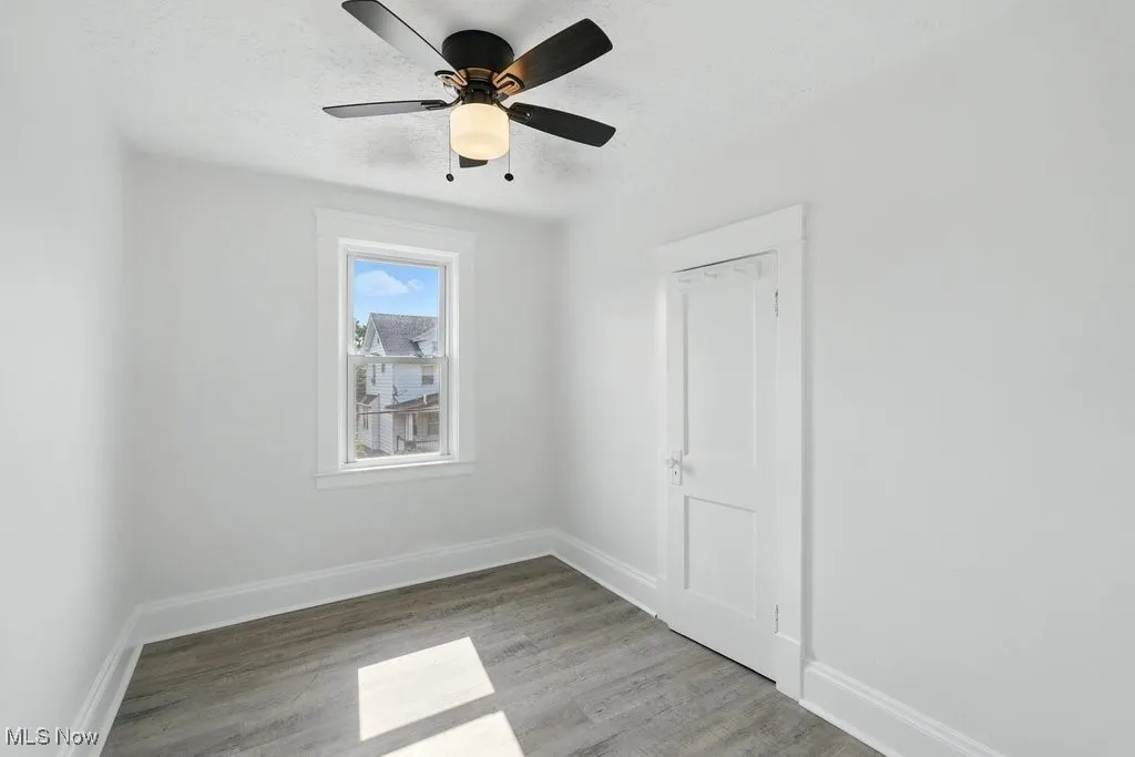 Spare room featuring light wood finished floors, baseboards, a textured ceiling, and a ceiling fan