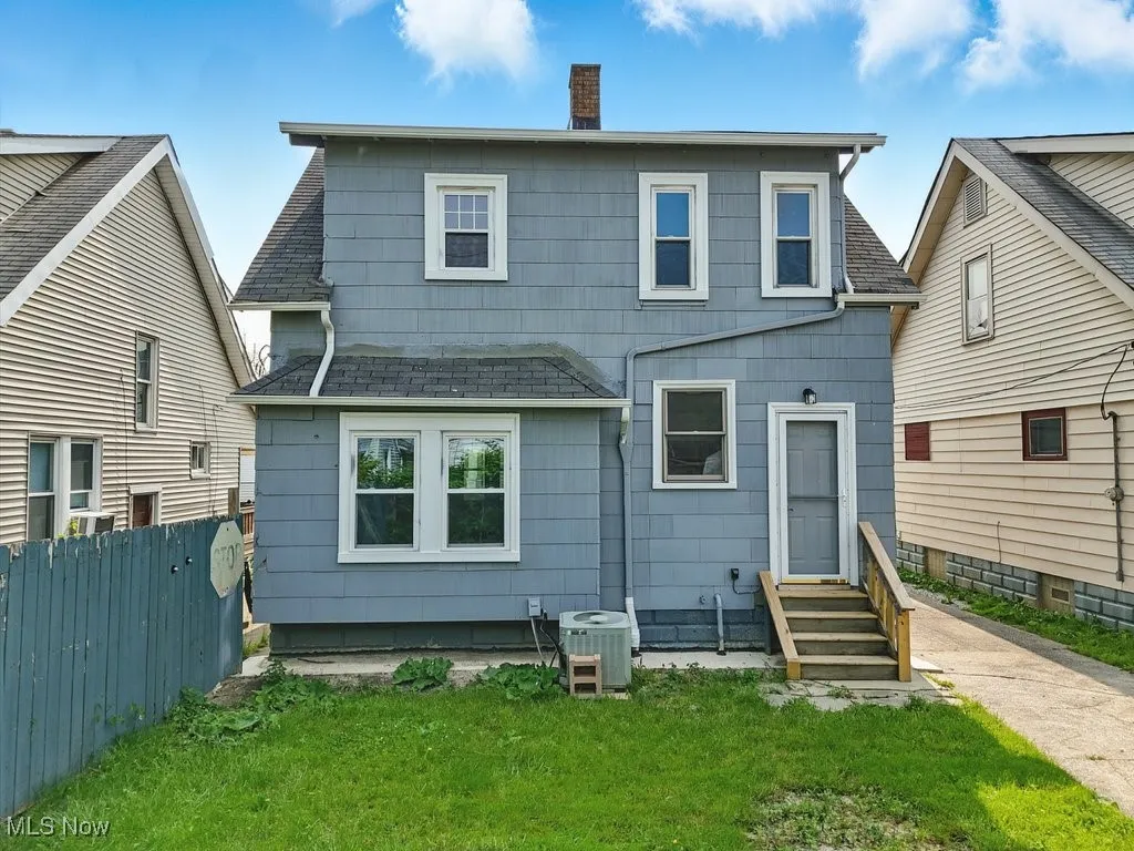 Back of property featuring entry steps, cooling unit, and a chimney