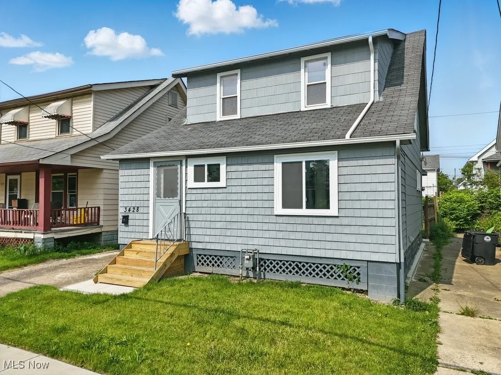 View of front of house featuring a shingled roof and a front lawn