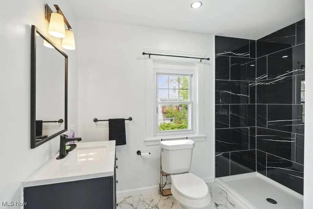Full bathroom with marble finish flooring, vanity, tiled shower, toilet, and recessed lighting