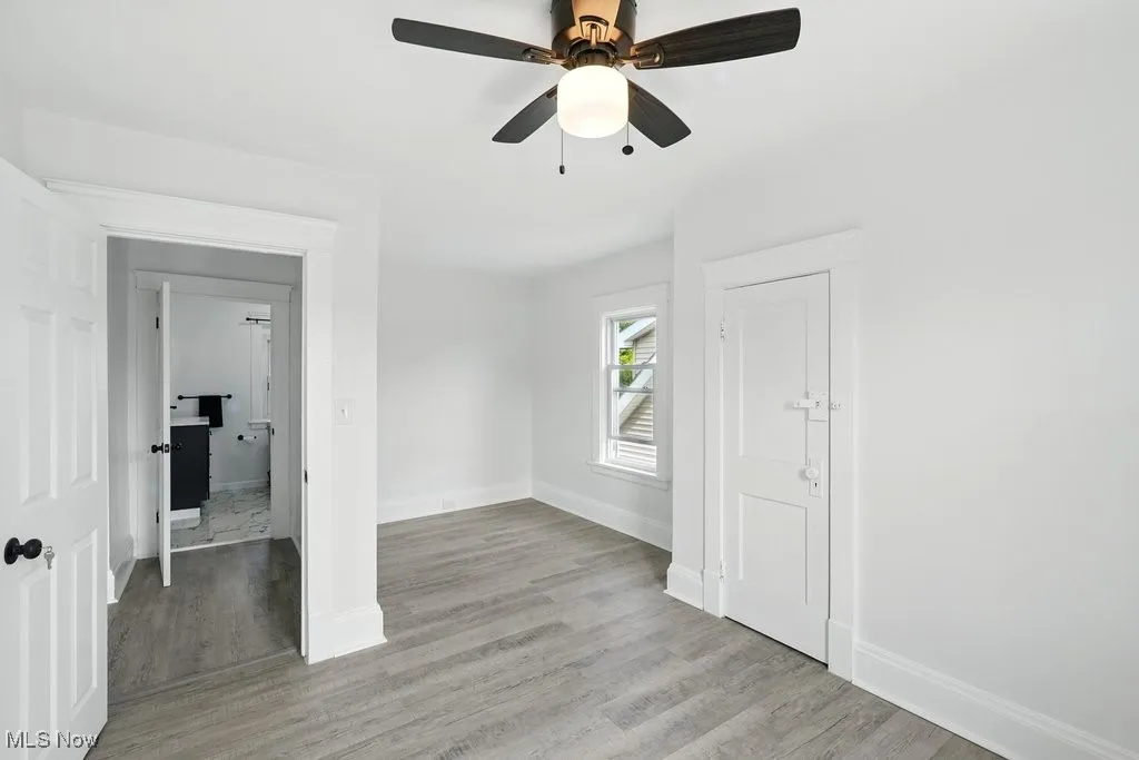 Spare room featuring light wood-style floors, baseboards, and a ceiling fan