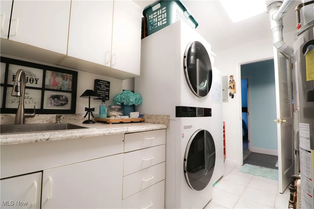 Efficient laundry room with custom made extra cabinetry, sink, stackable washer & dryer!