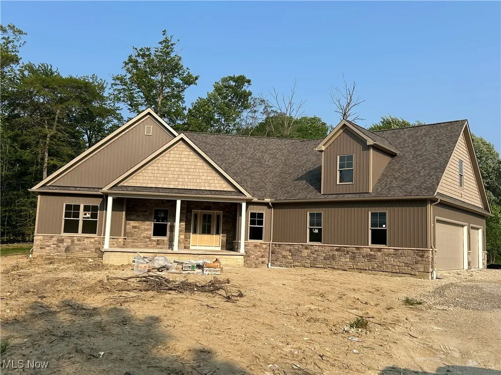 Craftsman house with stone siding, a porch, roof with shingles, and an attached garage