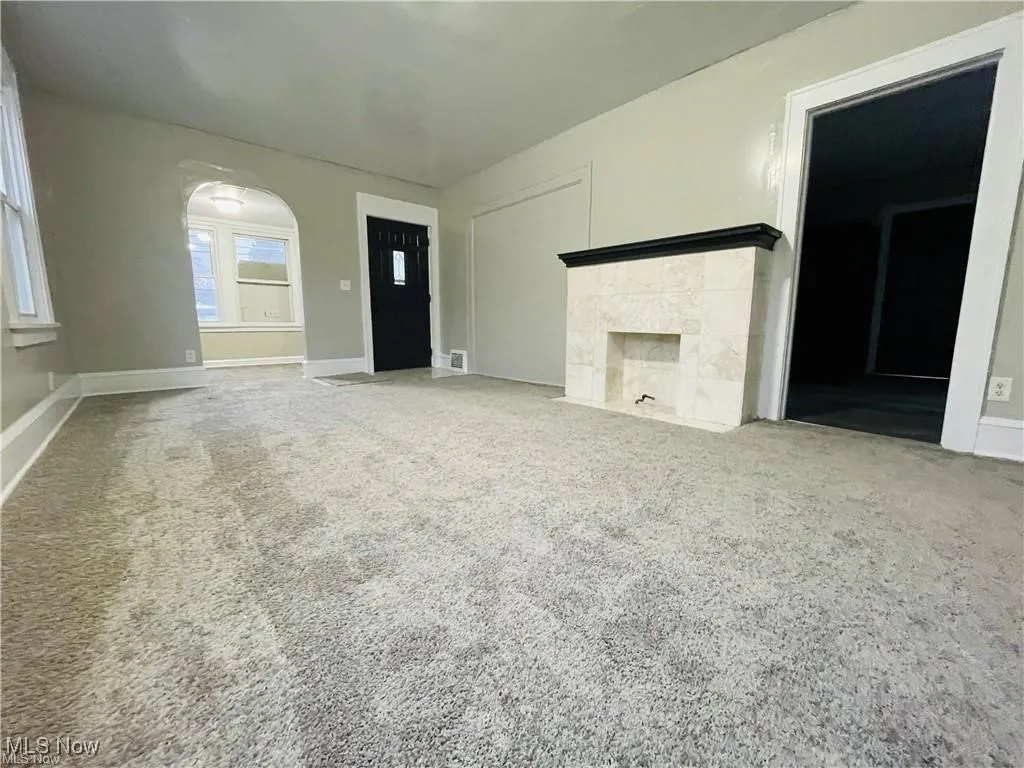 Unfurnished living room with carpet flooring, a tile fireplace, and baseboards