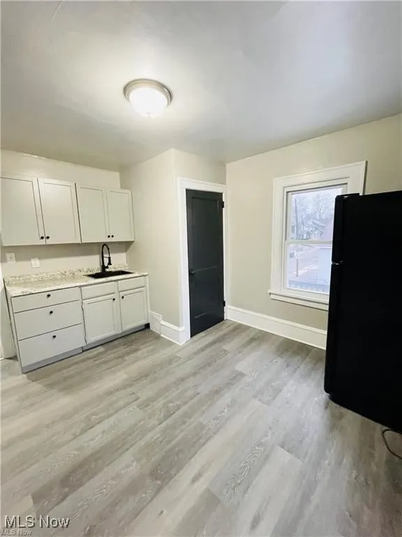 Kitchen featuring a sink, baseboards, freestanding refrigerator, light wood-type flooring, and light countertops