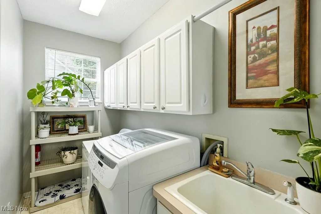 Main Floor Laundry with Sink, Washer, Dryer, and Cabinets