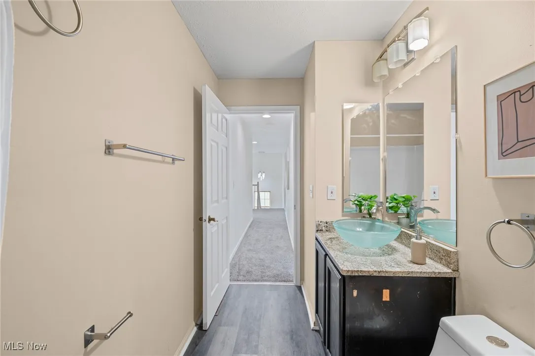 Bathroom with toilet, vanity, wood finished floors, and baseboards
