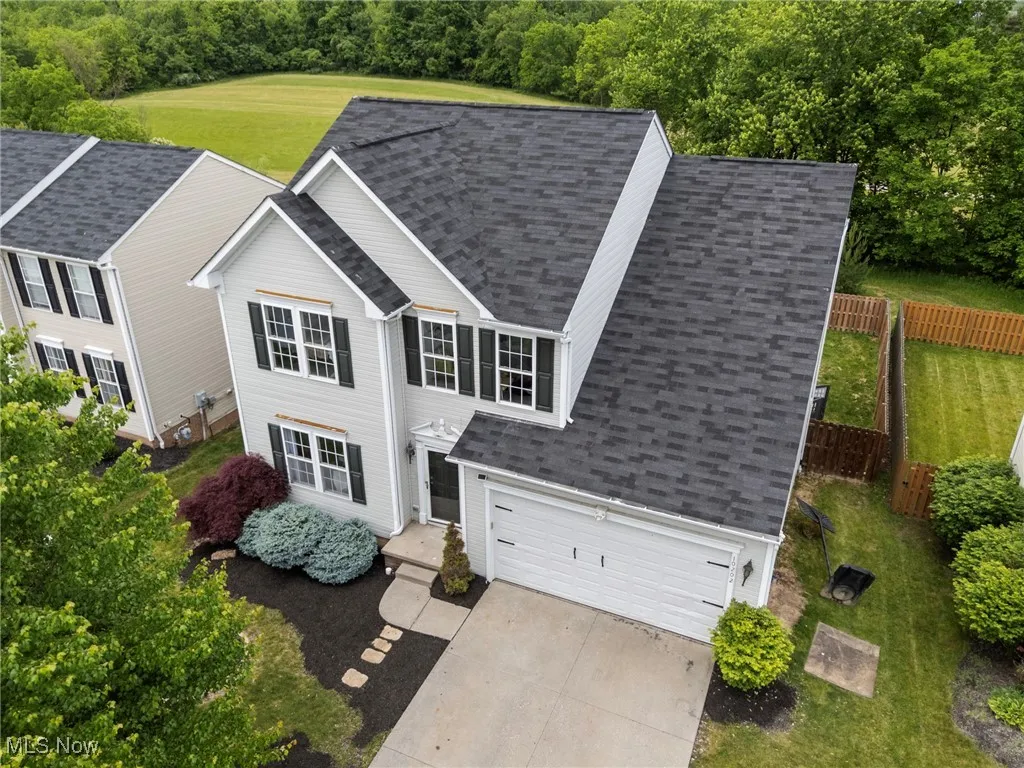 View of front of home with roof with shingles, an attached garage, and driveway