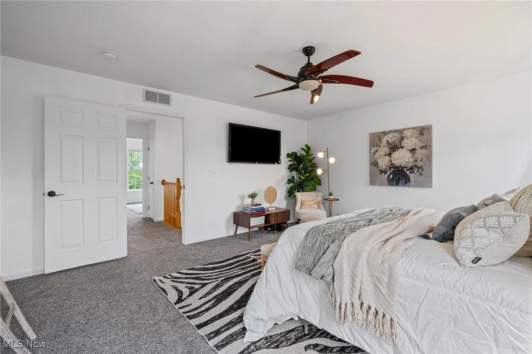 Carpeted bedroom featuring ceiling fan