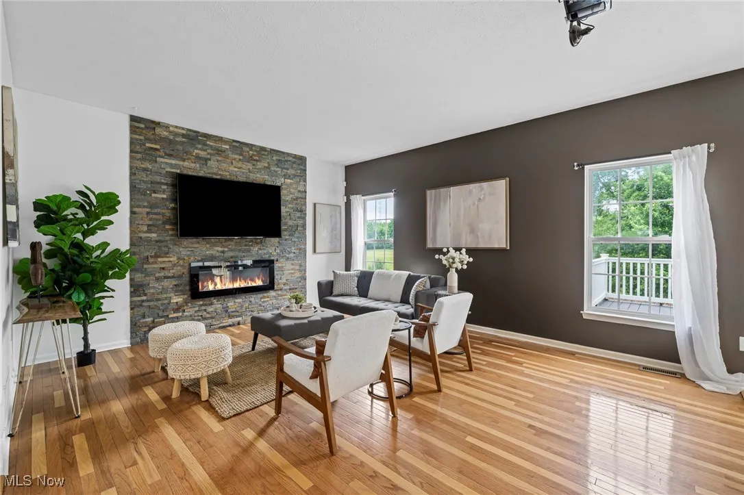 Living area featuring hardwood / wood-style flooring, a fireplace, baseboards, and an accent wall