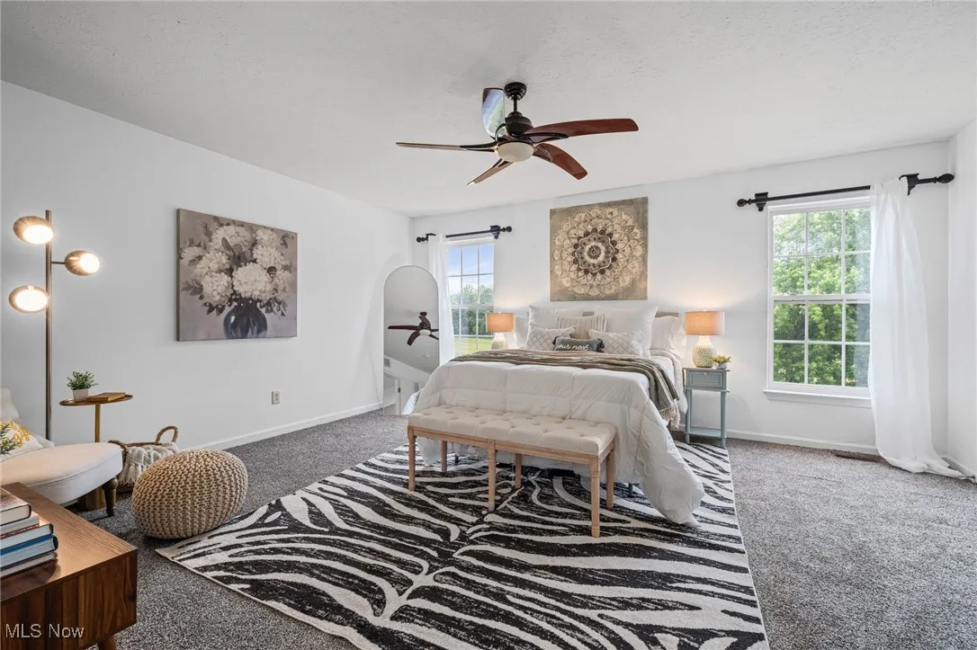 Bedroom featuring carpet floors, multiple windows, baseboards, and a ceiling fan