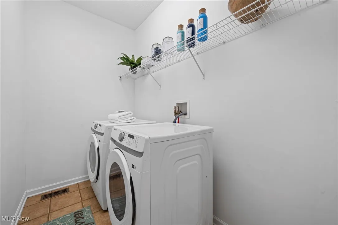 Laundry room featuring separate washer and dryer, baseboards, and light tile patterned floors