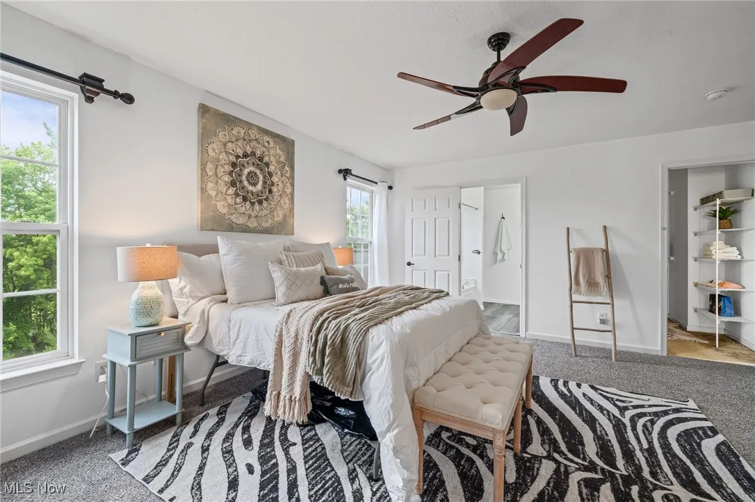 Carpeted bedroom with baseboards, ensuite bath, and a ceiling fan